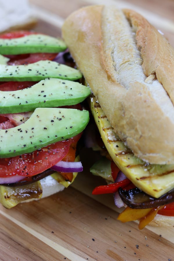 Grilled Veggie Sandwich has grilled yellow squash, portobello mushrooms, sautéed bell peppers, zesty hummus, goat cheese, tomatoes, avocados and onions all in a French baguette.