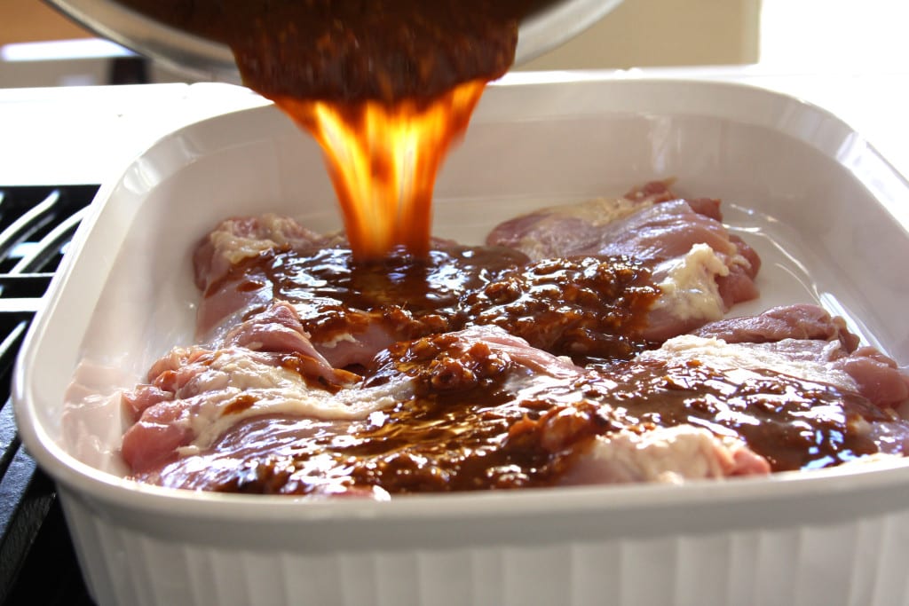 Pouring marinade over Asian Chicken Sriracha Bowl.