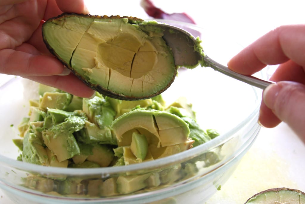 Scooping cut avocados for Simple Healthy Guacamole.