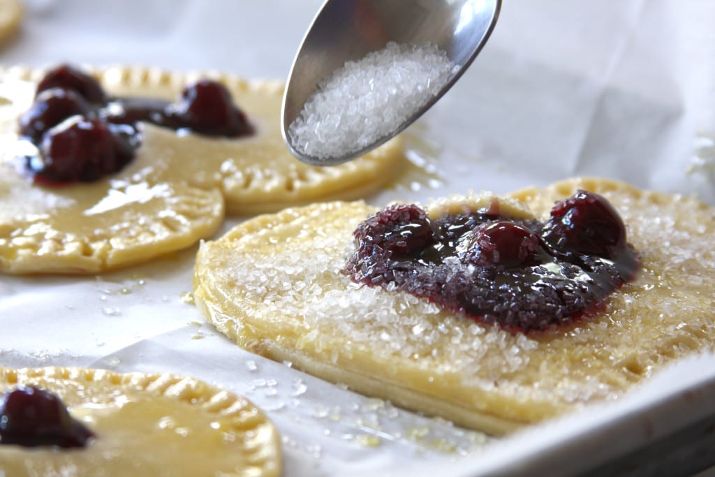 Sprinkling Sparkling sugar in Cherry Heart Pies.