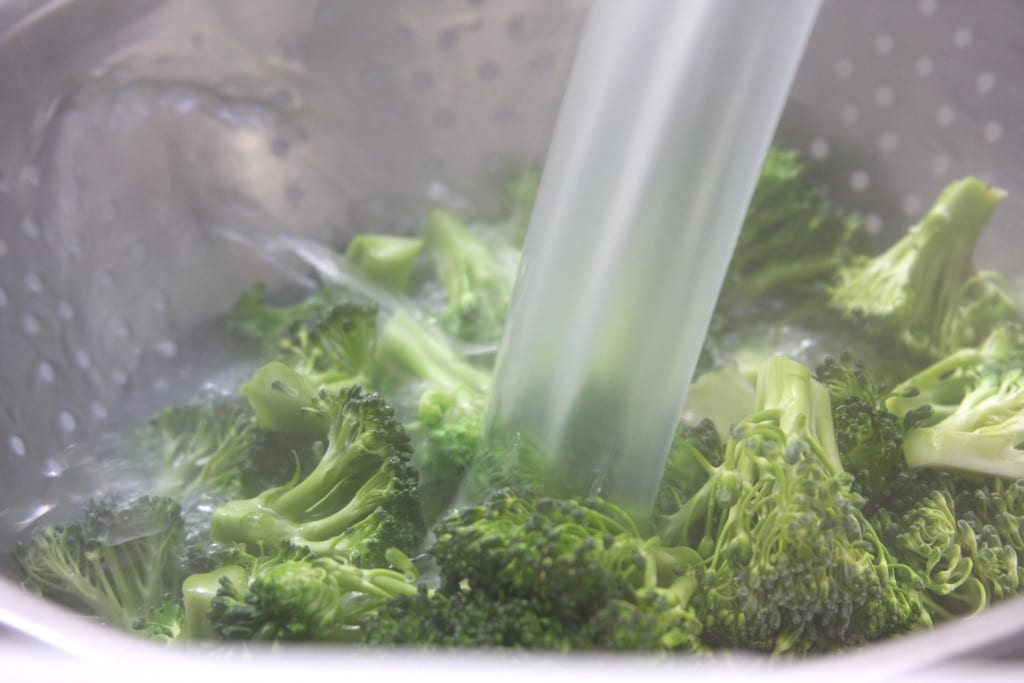 Blanching broccoli by pouring hot noodle water over the top for Springtime Pasta Salad.