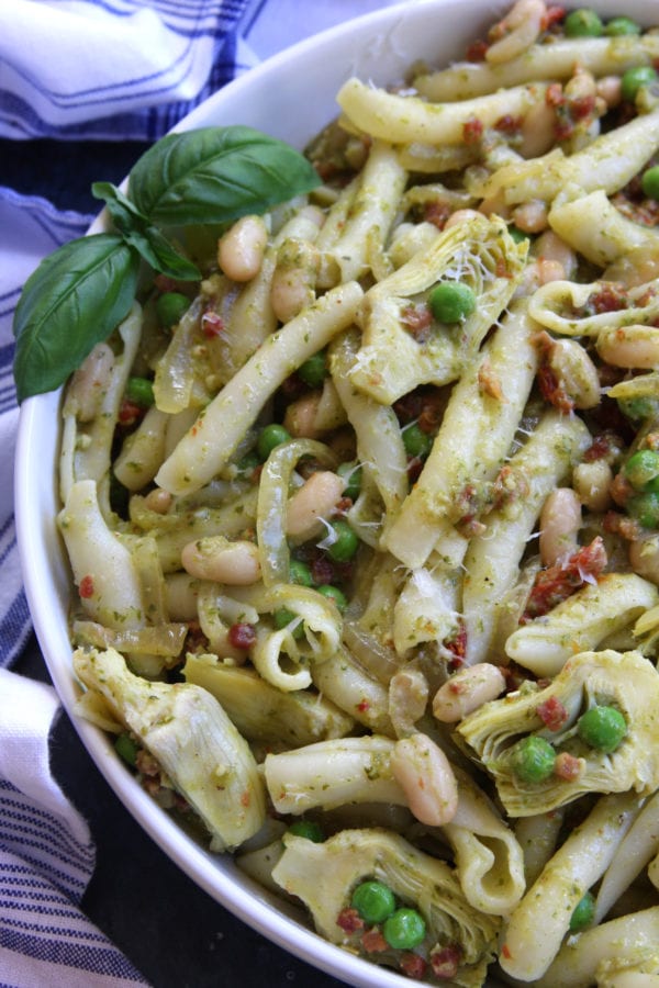 Hearty Tuscan Pasta recipe has cannellini beans, pancetta, sun-dried tomatoes, artichoke hearts, peas and pesto. Comes together within a half hour and is the perfect meal to impress company. This is my new favorite go to pasta.