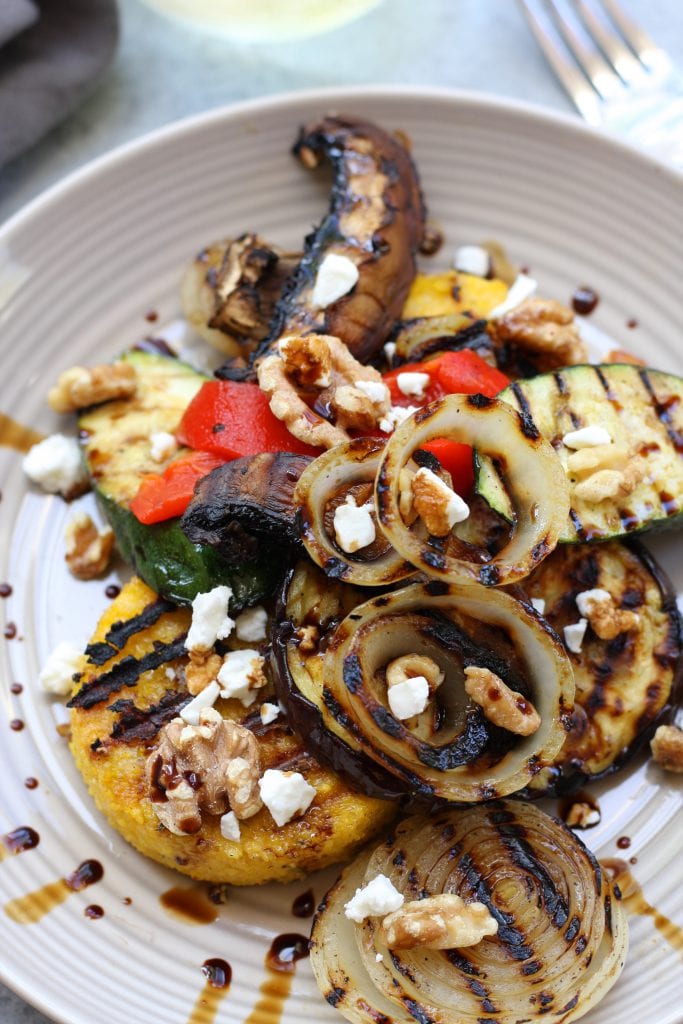 Rustic Italian Grilled Polenta & Vegetables recipe is a healthy & savory dish great for sharing. Polenta has flavors of rosemary and parmesan and is surrounded by grilled veggies and a balsamic reduction. Portable, tasty and vegetarian.