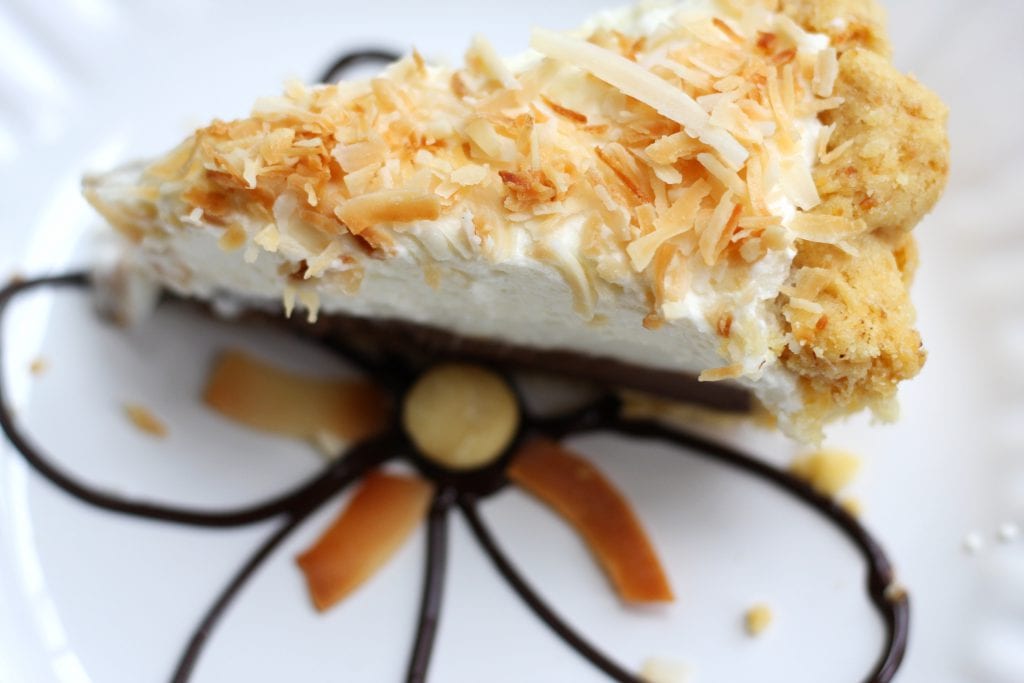 A cherished Hawaiian dessert,Haupia Pie with Macadamia Crust is as exciting to eat as attending your first luau. This gorgeous pie has a flaky and nutty crust, rich coconut chocolate layer, coconut cream layer all topped with fluffy whipped cream. You will be in heaven from the first bite.