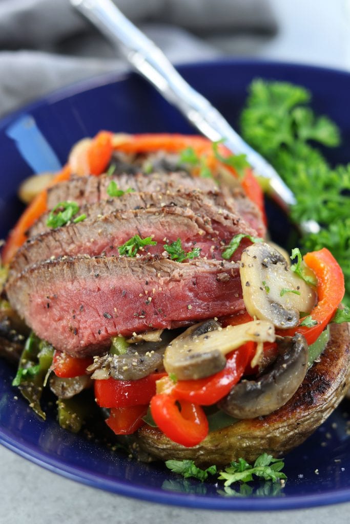 Veggie Cheesesteak Potatoes recipe has tender steak, red wine sautéed veggies, creamy homemade cheese sauce over a crispy potato.