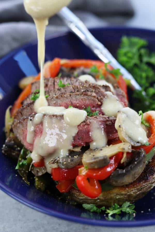 Veggie Cheesesteak Potatoes recipe has tender steak, red wine sautéed veggies, creamy homemade cheese sauce over a crispy potato.