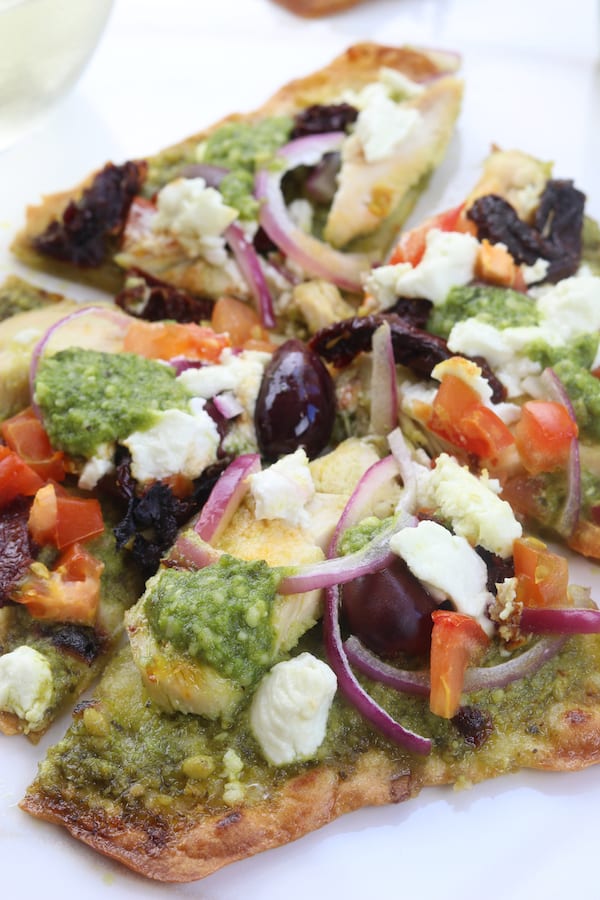 Easy and delicious, Chicken Pesto Naan Pizza comes together in minutes with kalamata olives, goat cheese and sun-dried tomatoes. Perfect for busy weeknights without composing flavor.