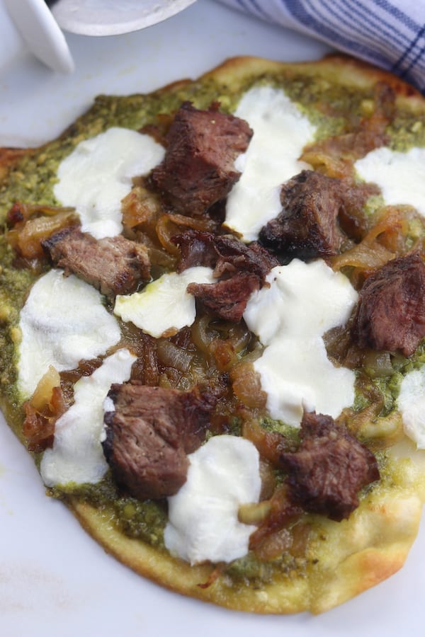 Caramelized Onion Steak Naan Pesto Pizza has the perfect marriage of sweet buttery caramelized onions, herby pesto and satisfying steak. Ingredients can be made ahead of time for a delicious dinner that comes together in a little over 10 minutes.