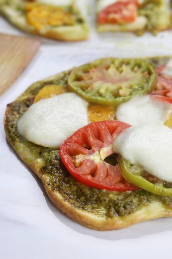 Light and summery, Heirloom Tomato Pesto Naan Pizza is a quick and easy recipe perfect for curing the take out cravings.