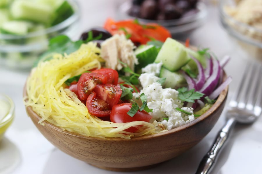 Spaghetti Squash Greek Bowls are an easy low fat and low-carb meal perfect for summer. Mix and match your favorite Greek toppings and drizzle on the popular dressing. You will love these!