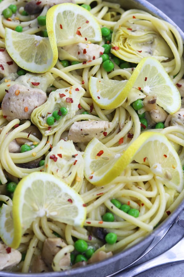 Skinny Lemon Chicken Pasta recipe is delicious enough for company and yet easy enough for a weeknight lighter meal. Tender chicken, artichoke hearts and peas are covered in a lemony garlic sauce. Serve with your favorite pasta, it is a favorite healthy decadent feast!