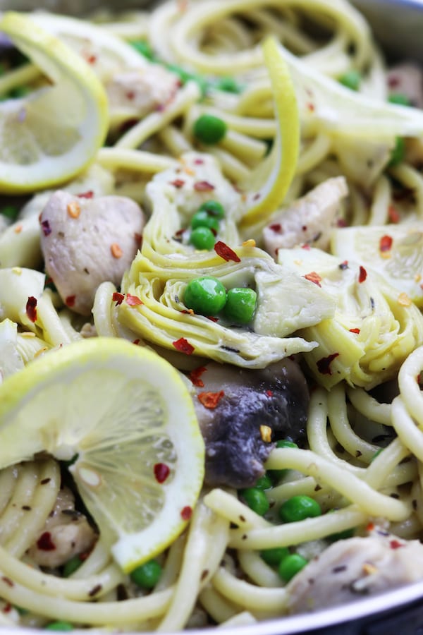 Skinny Lemon Chicken Pasta recipe is delicious enough for company and yet easy enough for a weeknight lighter meal. Tender chicken, artichoke hearts and peas are covered in a lemony garlic sauce. Serve with your favorite pasta, it is a favorite healthy decadent feast!