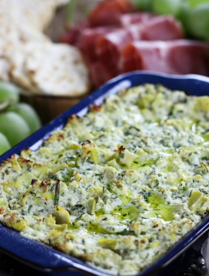 Lemon Artichoke Dip sitting among other appetizers