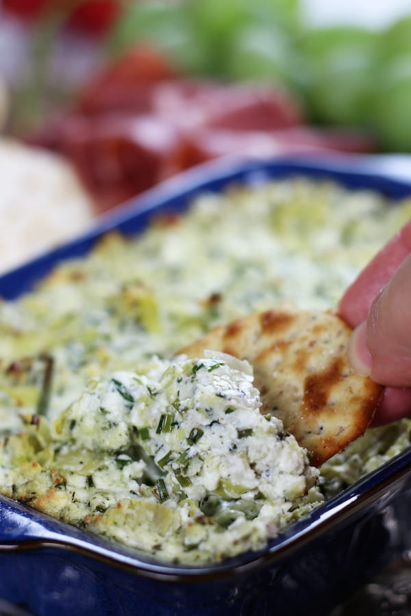 Scoping Lemon Feta Artichoke Dip with a cracker.