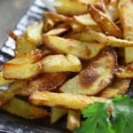 Homemade French Fries with ranch dressing on a dark plate.