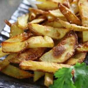 Homemade French Fries with ranch dressing on a dark plate.