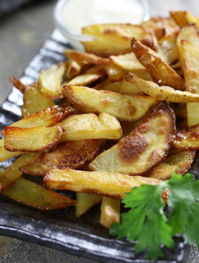 Homemade French Fries with ranch dressing on a dark plate.