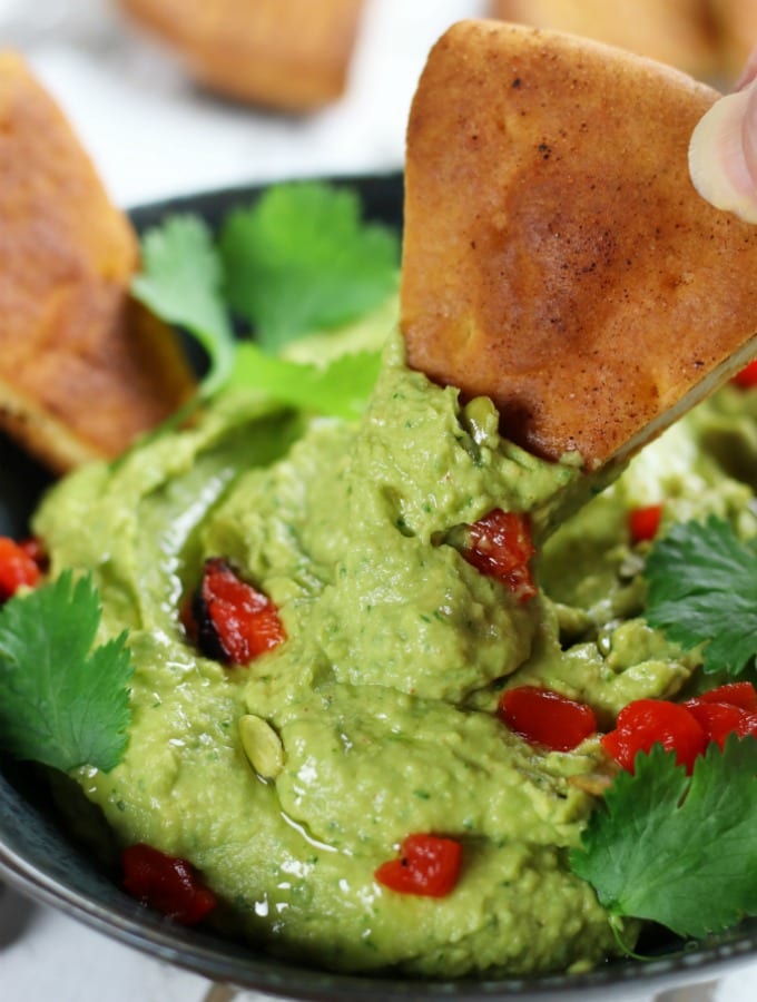 Pita chip dipping into Avocado Hummus.