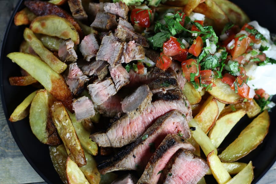 Overhead photo of Carne Asada French Fries with pico de gallo and sour cream.