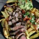 Overhead picture of Carne Asada Fries on a black plate.