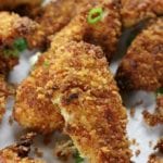 Several Fried Crispy Chicken Strips on parchment paper.