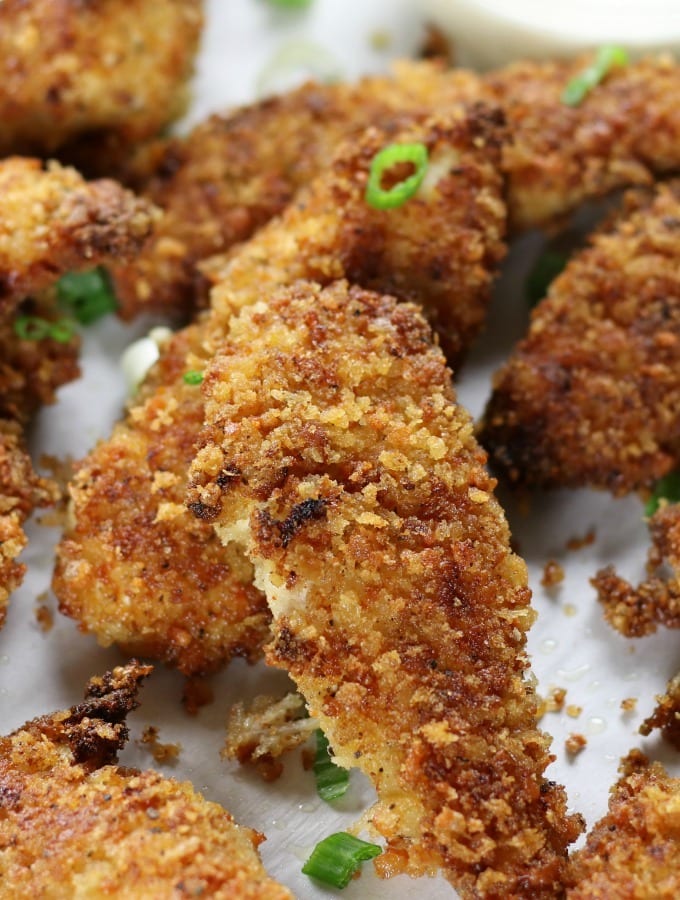 Several Fried Crispy Chicken Strips on parchment paper.