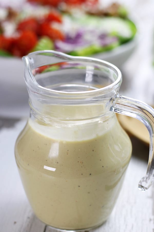 Bottle of Lemon Tahini Salad Dressing sitting on a table.