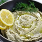 Up close photo of Lemon Dill Hummus in a dark bowl.