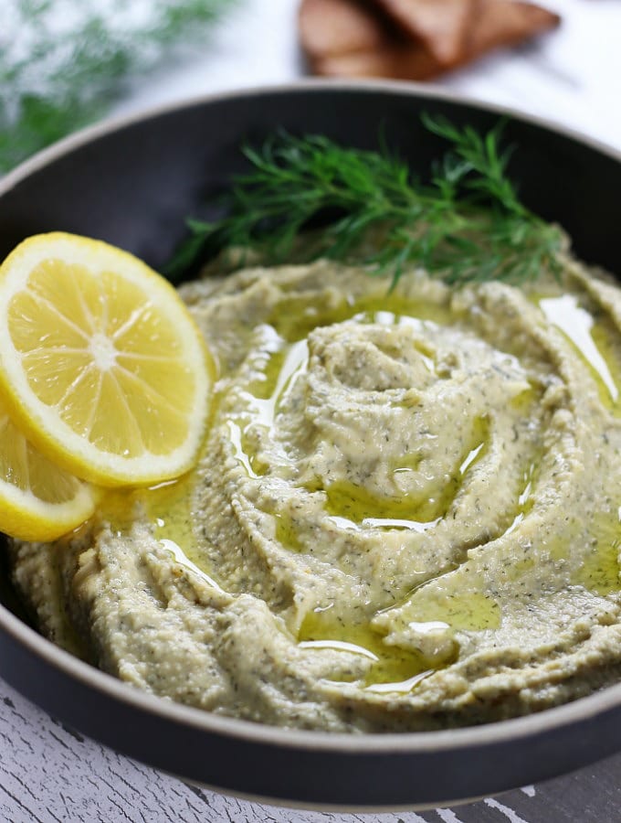 Up close photo of Lemon Dill Hummus in a dark bowl.