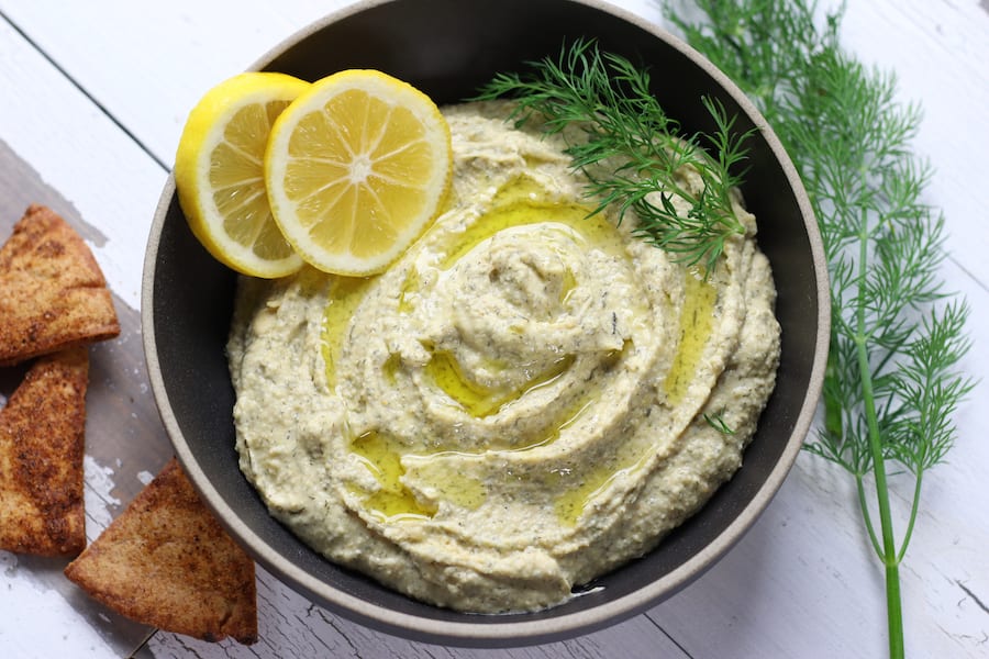 A bowl of Lemon Garlic Hummus sitting on a white table.