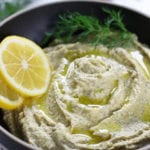 Lemon Hummus with a sprig of fresh dill and two slices of lemon.