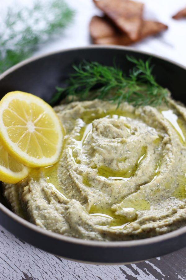 Lemon Hummus with a sprig of fresh dill and two slices of lemon.