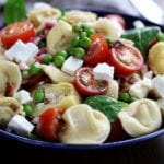 Tortellini Pasta Salad in a bowl with tomatoes, peas, bacon, feta and spinach.
