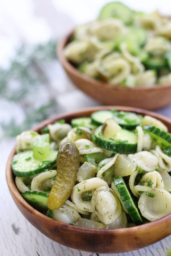 A bowl full of Dill Pasta Salad with cucumber coins and pickles.