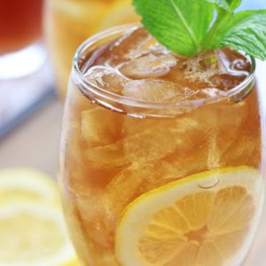 Glass full of Ice Tea with lemon slice and mint leaves.