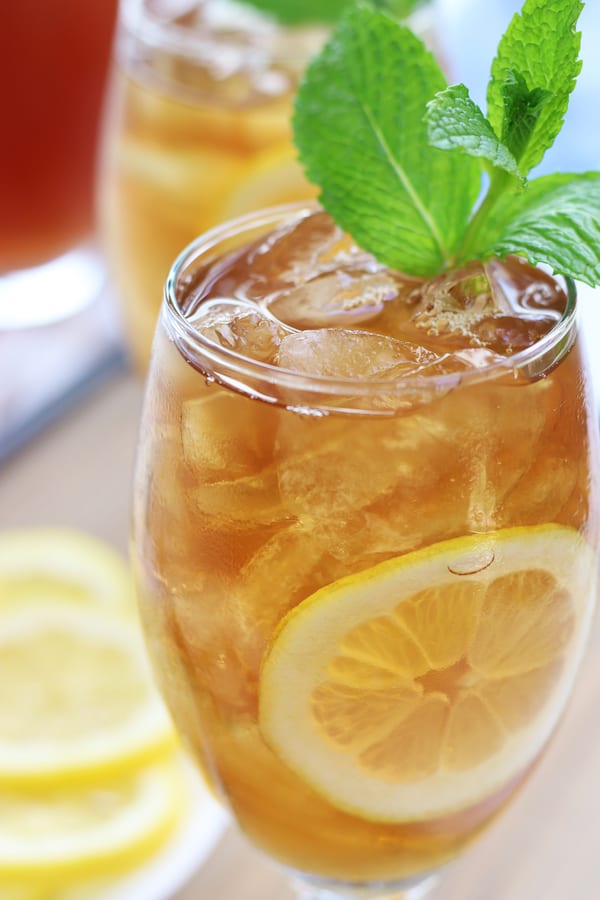 Glass full of Ice Tea with lemon slice and mint leaves.