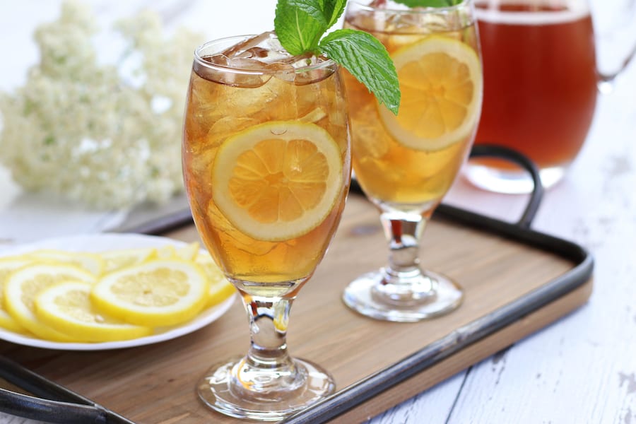 Two glasses of Iced Tea sitting on a tray with lemon slices.