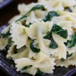 Simple Creamy Farfalle Pasta with Spinach on a grey wavy plate.