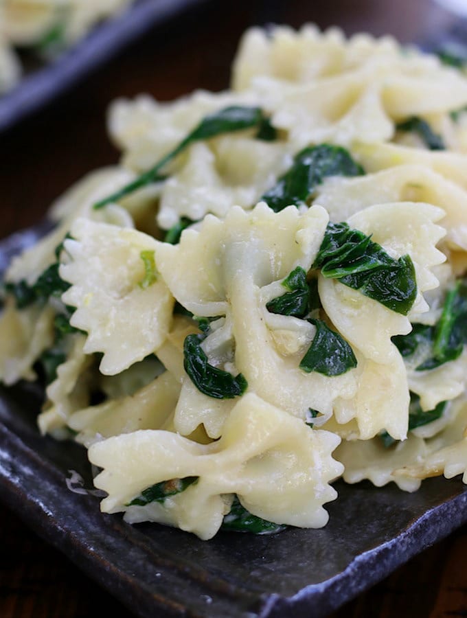 Simple Creamy Farfalle Pasta with Spinach on a grey wavy plate.