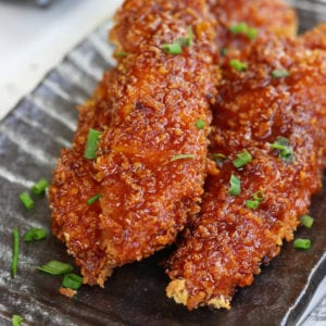 Three Sticky Chicken strips garnished with green onions.