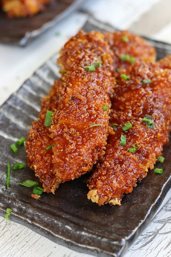 Three Sticky Chicken strips garnished with green onions.