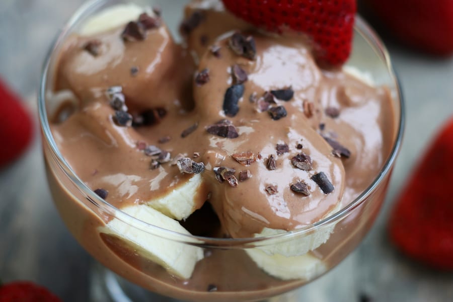 Overhead shot of a bowl of cut banana smothered with Chocolate Peanut Butter Fruit Dip.