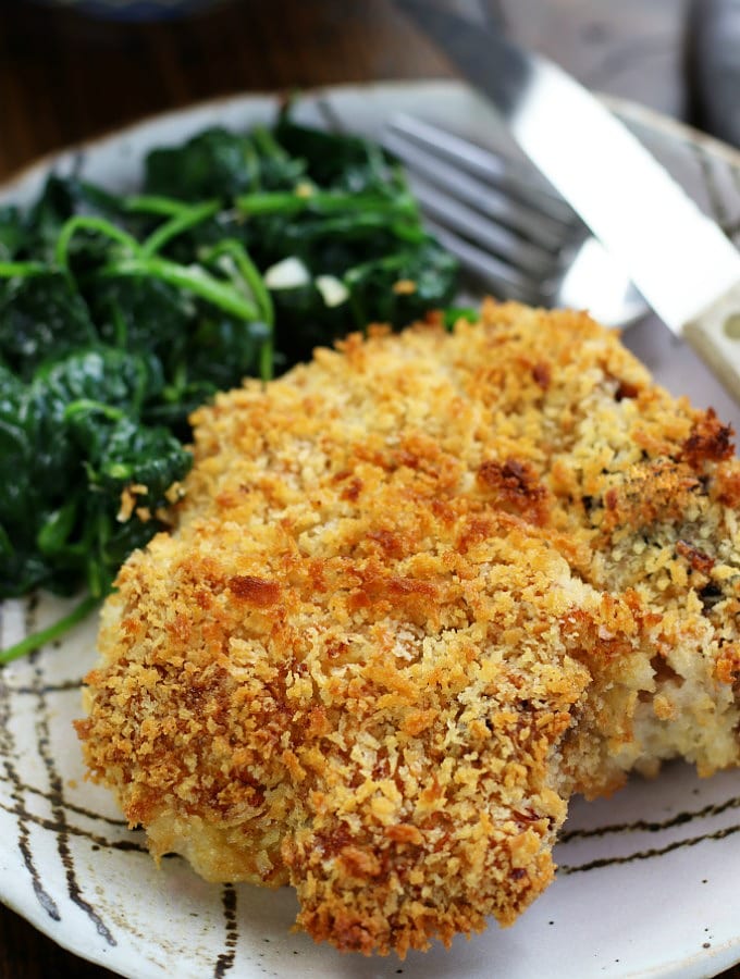 Crispy Baked Pork Chops recipe on a plate with spinach.