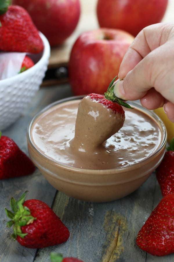 A strawberry being dipped into chocolate peanut butter Fruit Dip.