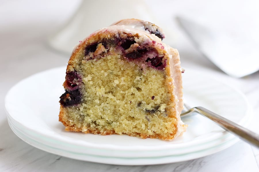 Lemon and Blueberry Cake slice on a white plate with a fork.