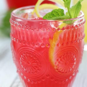 Pink Lemonade in a glass with mint and lemon twist.