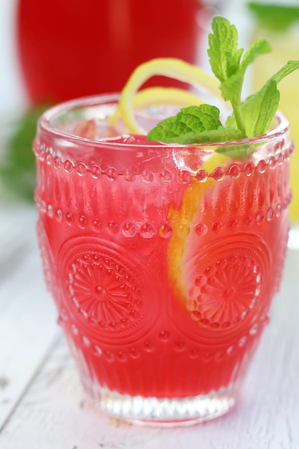 Pink Lemonade in a glass with mint and lemon twist.