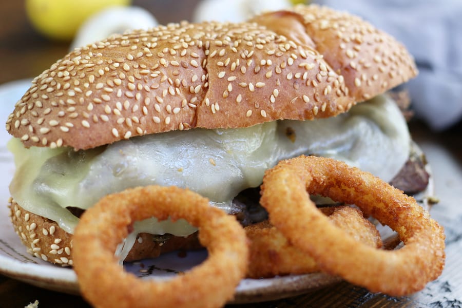 up close photo of Roast Beef Sandwich Recipe on a plate with onion rings.