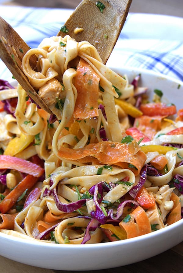 Tongs portioning out Chicken Peanut Udon Noodle Salad.