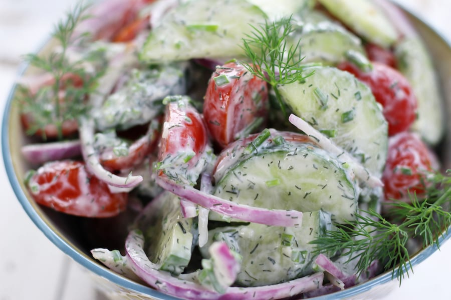 Creamy Cucumber Salad with red onion slices and fresh dill sprigs.